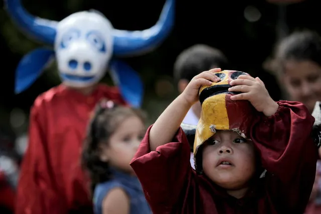 A child looks out from under his mask during the “Cavalhadas” festival in Pirenopolis, Brazil, Sunday, May 19, 2013. The popular festival, featuring masked horsemen, is a tradition that was introduced in the 1800's by a Portuguese priest to mark the the ascension of Christ. The 3-day festival reenacts the Christian knights' medieval defeat of the Moors. (Photo by Eraldo Peres/AP Photo)