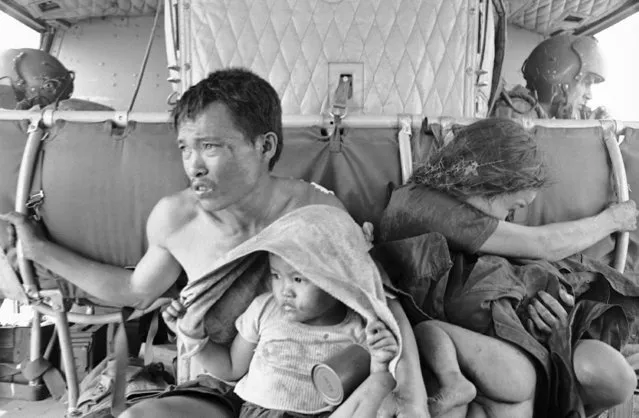 Vietnamese family hold tightly to one another and metal bars of American helicopter on April 27, 1966, as they are flown from home near Duc Ban to Song Be for medical treatment and interrogation. Family was found wounded hiding under shattered tree by U.S. Soldiers of 173rd Airborne Brigades 2nd Battalion after assault into are near Duc Ban where intelligence had said a large force of hard core Viet Cong were encamped. The man, Le Van Minh, was a farmer and possibly Viet Cong. (Photo by John Nance/AP Photo)