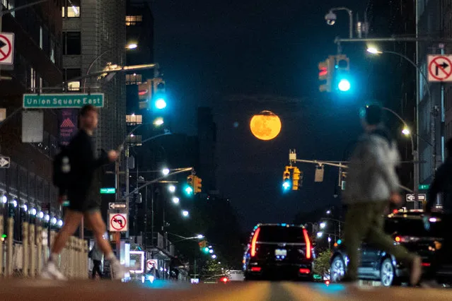The full Flower Moon rises as people make their way along 14st in New York City in New York, U.S., May 5, 2023. (Photo by Eduardo Munoz/Reuters)