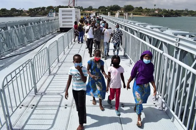 Members of the public walk across the newly commissioned Liwatoni Floating Foot Bridge in Mombasa, Kenya, Friday, January 1, 2021, which has been constructed by the Kenya National Highway Authority through the China City Construction Company. The floating foot bridge will decongest the crossing of the Likoni ferry Channel as only vehicles will be using the ferries and members of the public will be using this floating footbridge in both directions between the mainland and the Island. (Photo by Gideon Mandu/AP Photo)