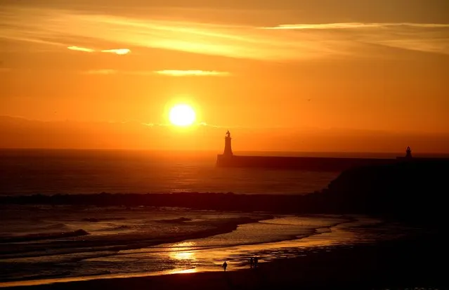 People enjoy the sunrise over Longsands beach in Tynemouth, UK, on December 3, 2014. (Photo by Owen Humphreys/PA Wire)