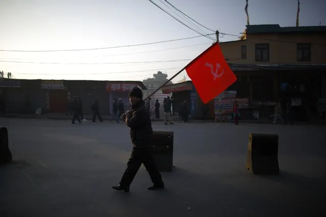 A protester holding a party flag walks along a road during the general strike independently called by the Unified Communist Party of Nepal (maoist) and led by 30 party alliance and  the Communist Party of Nepal (Maoist) demanding that the drafting of the new constitution is done on time on through consensus, in Kathmandu January 13, 2015. (Photo by Navesh Chitrakar/Reuters)