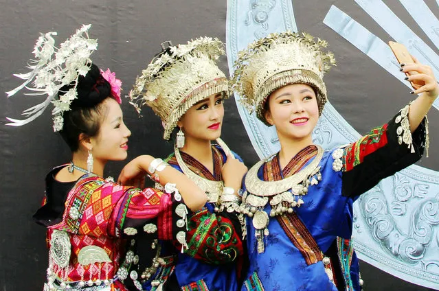 Young girls dress up in traditional costumes and pose for a selfie at the opening ceremony of the Leishan Miao new year festival in the city of Kaili, Guizhou province, China on November 23, 2015. (Photo by Imaginechina/Rex Shutterstock)