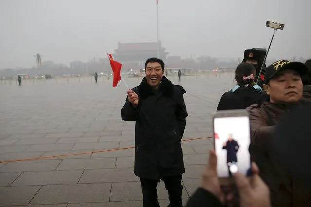 A man smiles as his picture is taken just after a flag-raising ceremony amid heavy smog at the Tiananmen Square, after the city issued its first ever "red alert" for air pollution, in Beijing December 9, 2015. (Photo by Damir Sagolj/Reuters)