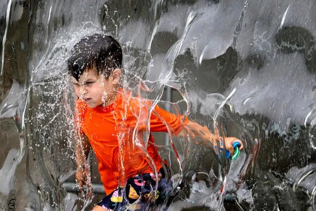 A young boy plays in the water fountain at Yards Park in Washington, DC, on June 26, 2023 as a heatwave settles in on the area. (Photo by Jim Watson/AFP Photo)
