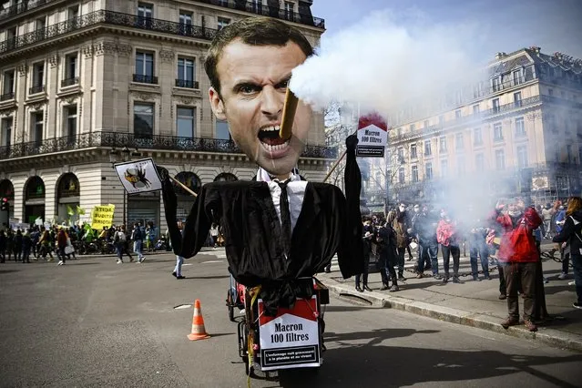 A puppet depicting French President Emmanuel Macron smoking a cigar and cigarette boxes reading in French “No filter Macron” is pictured as people gather to take part in a demonstration called country-wide by several NGOs and unions for a “true” law on climate, on March 28, 2021 in Paris. (Photo by Christophe Archambault/AFP Photo/Profimedia)