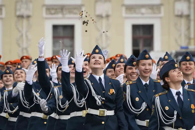 Russian Ministry of Emergency Situations Academy female graduates throw coins rejoicing at the end of the Academy during a parade marking 220th anniversary of the establishment of the fire department in St. Petersburg at the Palace Square in St. Petersburg, Russia, Friday, June 30, 2023. (Photo by Dmitri Lovetsky/AP Photo)