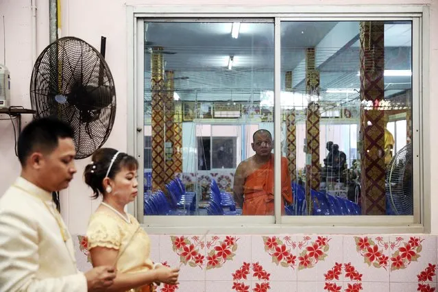 A Buddhist monk looks at a bride and a groom before they step into a pink coffin during their wedding ceremony at Wat Takien temple in Nonthaburi province, on the outskirts of Bangkok February 14, 2015. (Photo by Damir Sagolj/Reuters)