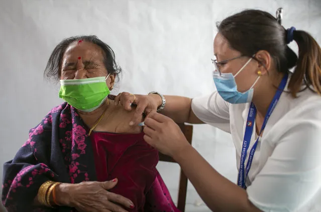 An elderly woman receives a dose of Covishield COVID-19 vaccine in Kathmandu, Nepal, Sunday, March 7, 2021. Nepal's Prime Minister Khadga Prasad Oli took the COVID-19 vaccine Sunday to start the country's campaign to inoculate the elderly population. (Photo by Niranjan Shrestha/AP Photo)