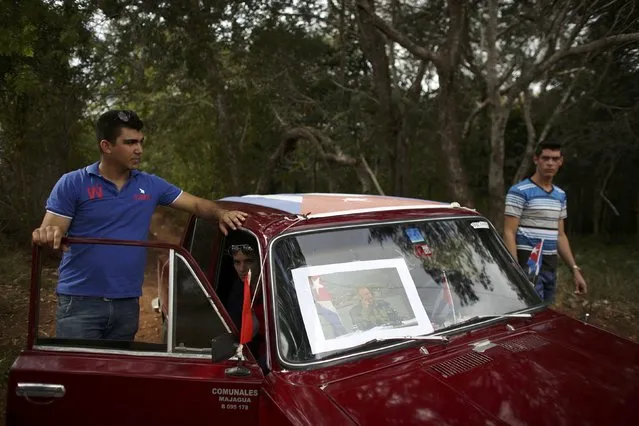 People cover a car with a Cuban flag and an image of Fidel Castro as they await the arrival of the caravan carrying the late Cuban President's ashes in El Maja, Cuba, December 1, 2016. (Photo by Alexandre Meneghini/Reuters)