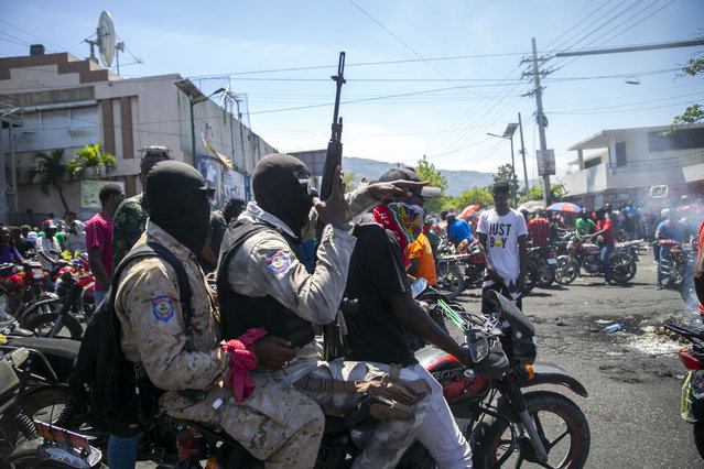 Armed and masked police officers move forward on a motorcycle during a protest by a disgruntled sector of the Haitian police force known as Fantom 509, in Port-au-Prince, Haiti, Wednesday, March 17, 2021. (Photo by Dieu Nalio Chery/AP Photo)