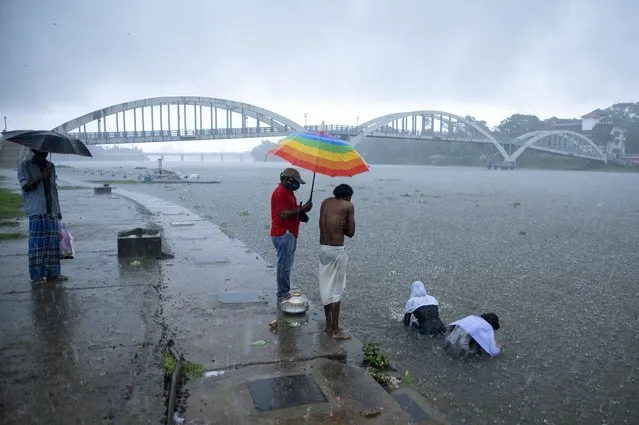 Relatives of a person who died of reasons other than COVID-19 perform rituals in Periyar river during heavy rains in Kochi, Kerala state, India, Saturday, May 15, 2021. With cyclonic storm “Tauktae” intensifying over the Arabian Sea, the southern state is receiving heavy rains amid a lockdown imposed to curb the spread of coronavirus. (Photo by R.S. Iyer/AP Photo)