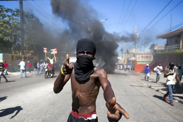 In this October 17, 2018 photo, a masked man joins a protests demanding to know how Petro Caribe funds have been used by the current and past administrations, in Port-au-Prince, Haiti. Much of the financial support to help Haiti rebuild after the 2010 earthquake comes from Venezuela's Petro Caribe fund, a 2005 pact that gives suppliers below-market financing for oil and is under the control of the central government. (Photo by Dieu Nalio Chery/AP Photo)