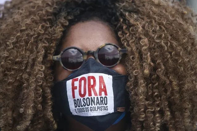 A woman wears a protective face mask designed with text that reads in Portuguese: “Bolsonaro out and all coup plotters”, during a protest against the government's response in combating COVID-19, demanding the impeachment of Bolsonaro, in Rio de Janeiro, Brazil, Saturday, May 29, 2021. (Photo by Bruna Prado/AP Photo)