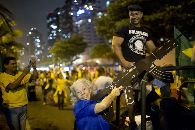 A supporter of presidential candidate Jair Bolsonaro poses for a photo with an oversized, fake rifle, as she celebrates the election runoff results in Rio de Janeiro, Brazil, Sunday, October 28, 2018. (Photo by Silvia Izquierdo/AP Photo)