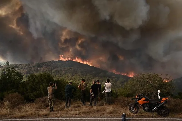 People look at the wildfire raging in a forest in Sikorahi, near Alexandroupoli, northern Greece, on August 23, 2023. Greek firefighters on August 23, 2023 struggled to contain uncontrolled fires throughout the country for a fifth day, several of them bordering an acrid, smoke-filled Athens. (Photo by Sakis Mitrolidis/AFP Photo)