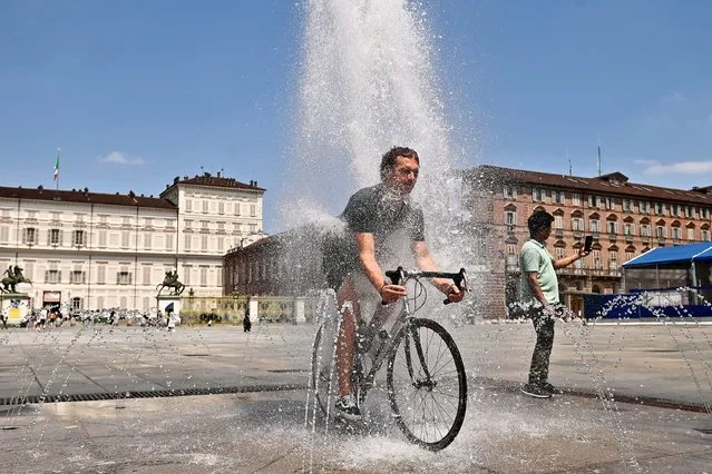 A man rides a bicycle inside a fountain in Piazza Castello on July 11, 2023 in Turin, Italy. The record for the highest temperature in European history was broken in August 2021, when 48.8C was registered in Floridia, a town in Italy's Sicilian province of Syracuse. (Photo by Stefano Guidi/Getty Images)