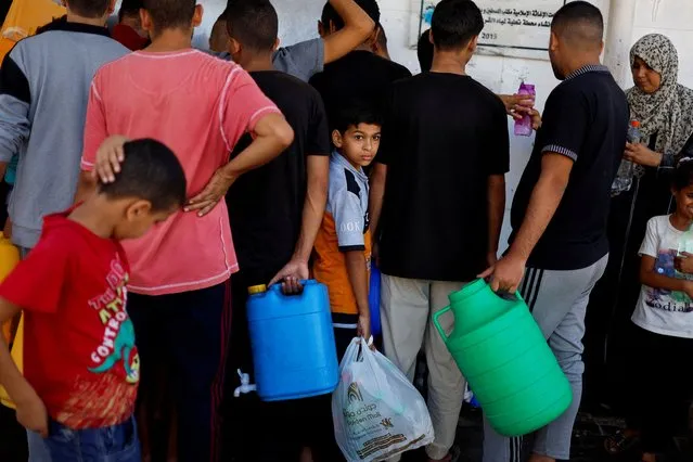 Palestinians gather to collect water, amid shortages of drinking water, as the Israeli-Palestinian conflict continues, in Khan Younis in the southern Gaza Strip on October 15, 2023. (Photo by Mohammed Salem/Reuters)
