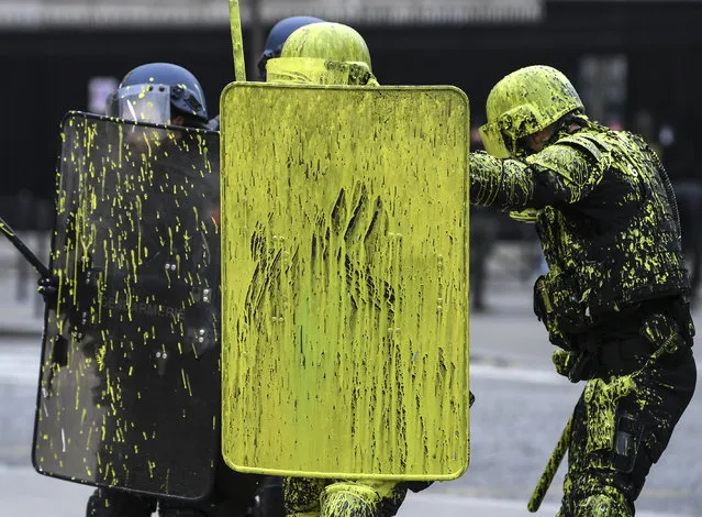 Riot police officers are covered with painting during clashes with demonstrators as part of a protest of Yellow vests (Gilets jaunes) against rising oil prices and living costs on the Champs Elysees in Paris, on December 1, 2018. Thousands of anti-government protesters are expected today on the Champs-Elysees in Paris, a week after a violent demonstration on the famed avenue was marked by burning barricades and rampant vandalism that President Emmanuel Macron compared to “war scenes”. (Photo by Alain Jocard/AFP Photo)