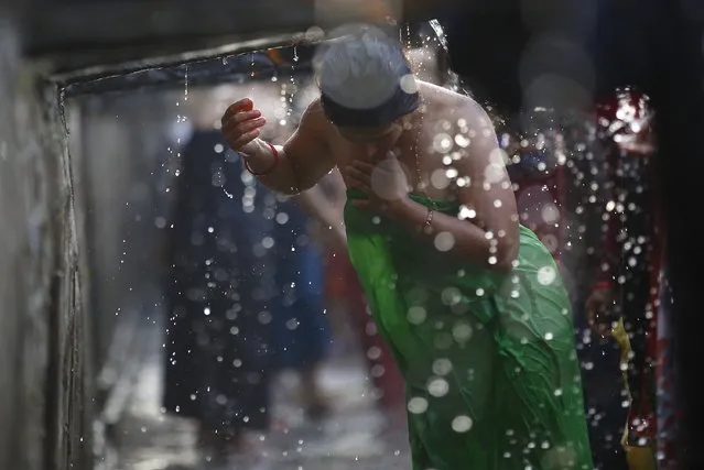 A devotee takes a holy bath at the Balaju Baise Dhara (22 water spouts) during the Baishak Asnan festival in Kathmandu April 4, 2015. Devotees believe that the water from these stone spouts, which is collected from the catchment area of the Nagarjun forest behind the spouts, will cure pains and skin diseases. (Photo by Navesh Chitrakar/Reuters)