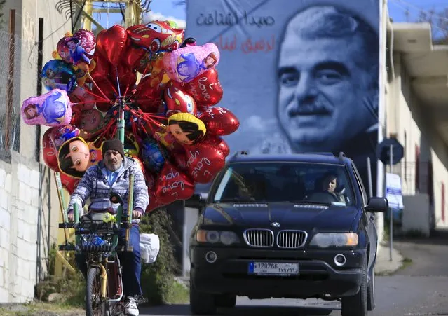 A street vendor sells balloons as he rides a motorbike past a billboard of Lebanon's assassinated former Prime Minister Rafik al-Hariri ahead of Valentine's Day in Sidon, southern Lebanon February 12, 2016. (Photo by Ali Hashisho/Reuters)