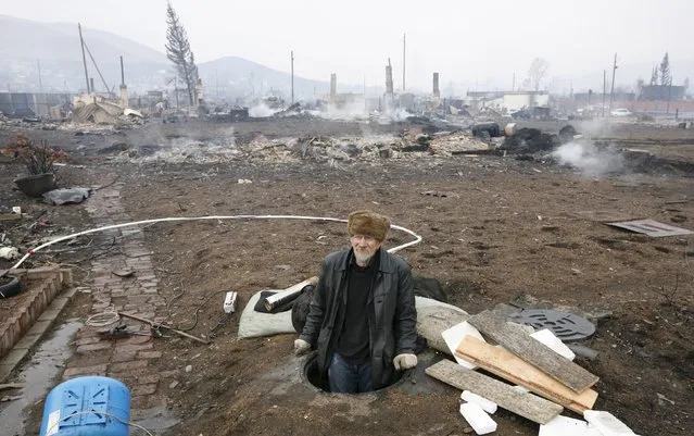 A man looks out from a downhole in the settlement of Shyra, damaged by recent wildfires, in Khakassia region, April 13, 2015. (Photo by Ilya Naymushin/Reuters)