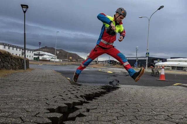 A member of search and rescue team jumps over the crack in a road in the fishing town of Grindavik, which was evacuated due to volcanic activity, in Iceland on November 15, 2023. (Photo by Marko Djurica/Reuters)