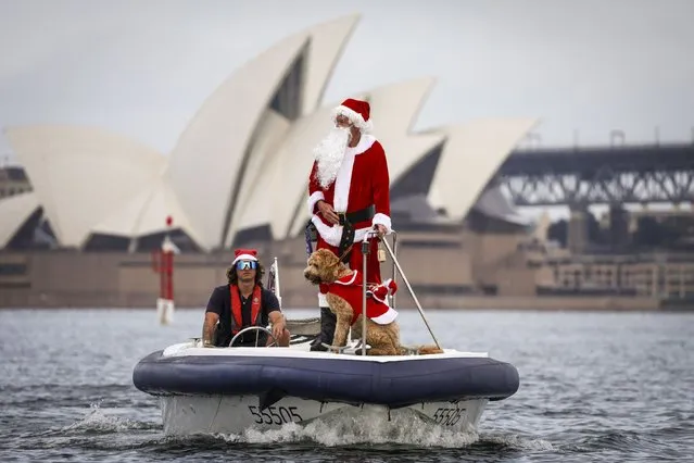 A man dressed as Santa Claus rides a boat with his dog in front of the Sydney Opera House, as part of Christmas Day celebrations for the annual Sydney to Hobart yacht race on December 25, 2023. (Photo by David Gray/AFP Photo)