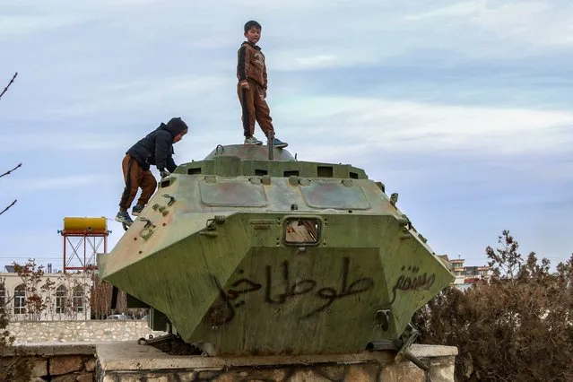Afghan boys play on the wreckage of a Soviet-era tank along a road at a military museum in Ghazni on January 4, 2024. (Photo by Mohammad Faisal Naweed/AFP Photo)