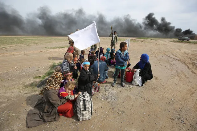Displaced Iraqi families gather as they flee a military operation by Iraqi security personnel aimed at retaking areas from Islamic State group jihadists, in the desert west of the city of Samarra on March 3, 2016. Counter-terrorism forces, soldiers, police and allied paramilitaries are taking part in an operation launched on March 1, which is backed by artillery and both Iraqi and US-led coalition aircraft, aimed at retaking areas north of Baghdad, according to the Joint Operations Command. (Photo by Ahmad Al-Rubaye/AFP Photo)