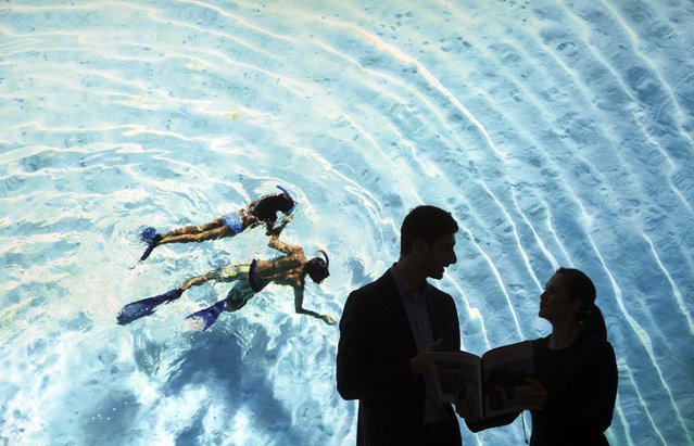 Two people stand in front of an oversized photo of two people snorkeling in the South Pacific at the booth from Tahiti during the ITB Berlin international travel trade show in Berlin, Germany, 09 March 2016. Around 10,000 exhibitors from more than 180 countries are presenting their new offers in the travel industry from 09 until 13 March 2016. The Maldives are the official partner country at the ITB this year. (Photo by Soeren Stache/EPA)