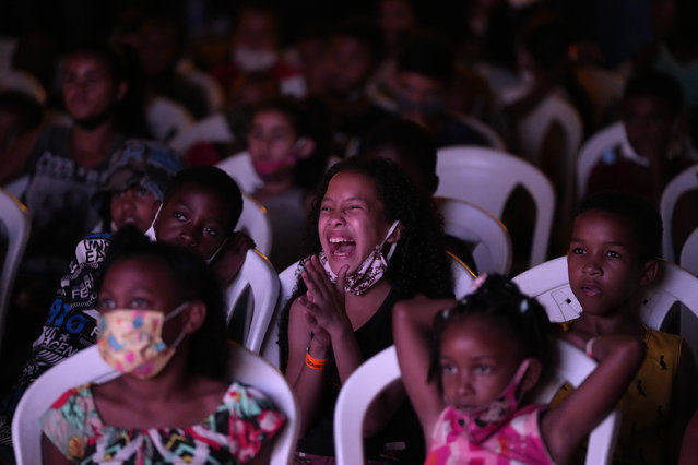 Children watch a movie of the “Cinema no Morro” or Cinema on the hill project at a cultural center at the Vila Cruzeiro favela of Rio de Janeiro, Brazil, Monday, September 13, 2021. The Cinema on the hill is a project provided by the Voz da Comunidade NGO, to screen movies for children from the  favelas. (Photo by Silvia Izquierdo/AP Photo)