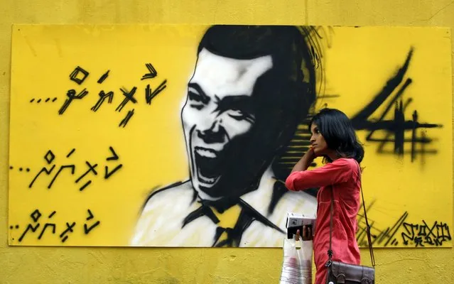 In this September 5, 2013, file photo, a woman walks past a graffiti of former President Mohamed Nasheed in Male, Maldives. Maldives has been in a political turmoil since last year's February resignation of Nasheed, who was elected in 2008 in the nation's first democratic polls after 30 years of autocracy. (Photo by Sinan Hussain/AP Photo)