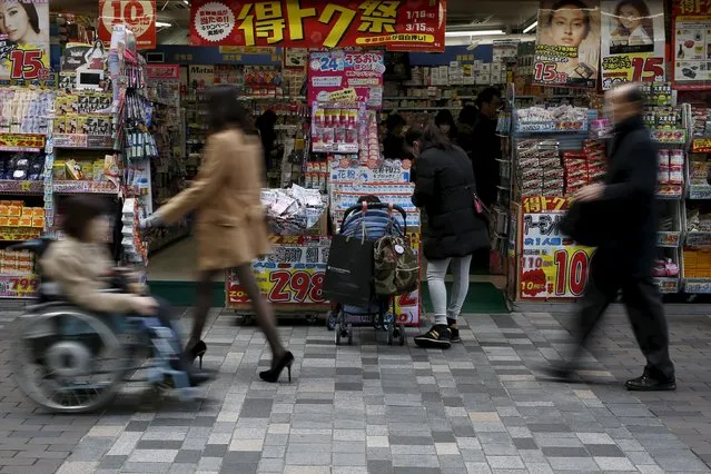 A woman with a baby buggy looks at items outside a discount store at a shopping district in Tokyo, Japan, February 25, 2016. Japan's core consumer prices were unchanged in January from a year earlier, suggesting that persistent falls in energy costs will keep inflation well below the central bank's 2 percent target. (Photo by Yuya Shino/Reuters)