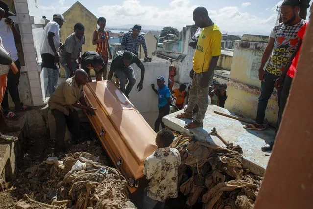 Relatives bury a woman who died in the hospital from her burn injuries caused by a gasoline truck that overturned and exploded, killing dozens in Cap-Haitien Haiti, Wednesday, December 15, 2021. (Photo by Joseph Odelyn/AP Photo)