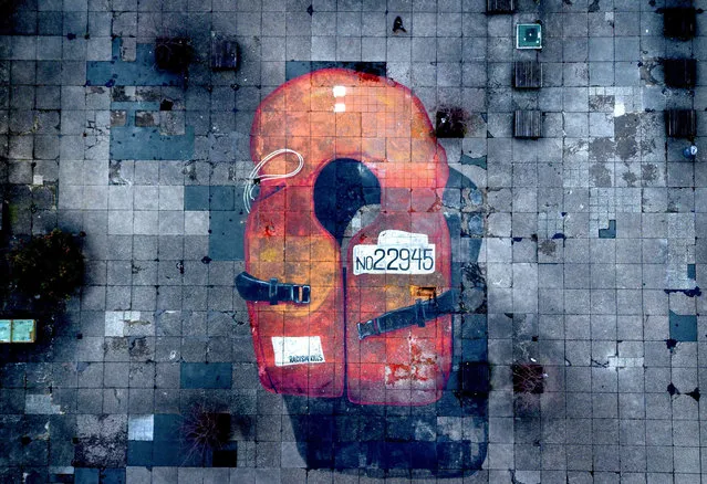 A 12x20m large painting of a life jacket is still seen on the ground of the university campus in Frankfurt, Germany, Friday, March 1, 2024. Artists of the “Kollektiv ohne Namen'” (collective without name) painted the life jacket three years ago to protest against the EU's migration policy in the Mediterranean Sea. (Photo by Michael Probst/AP Photo)