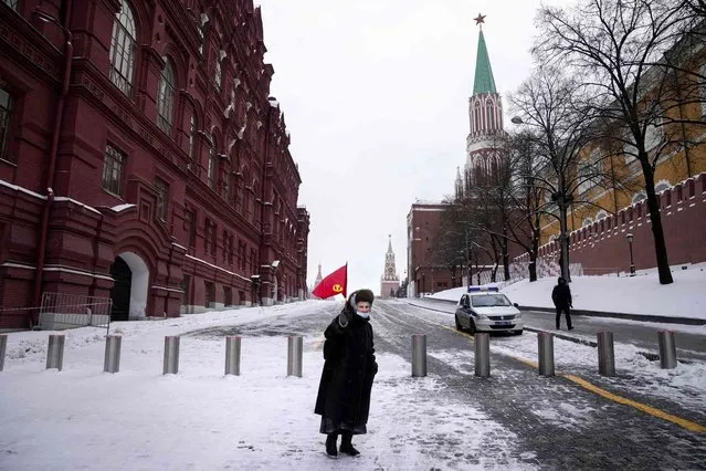 An elderly communist supporter with a former Soviet Union red flag waits to lay flowers at the grave Soviet leader Josef Stalin on the occasion of the 142nd anniversary of his birth near the Kremlin Wall in Red Square with Lenin's mausoleum on the right in Moscow, Russia, Tuesday, December 21, 2021. (Photo by Alexander Zemlianichenko/AP Photo)