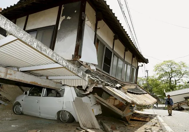 A man walks near a damaged house and car caused by an earthquake in Mashiki town, Kumamoto prefecture, southern Japan, in this photo taken by Kyodo April 15, 2016. (Photo by Reuters/Kyodo News)