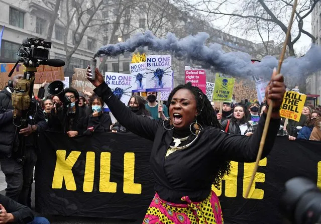 A demonstrator holds up a flare as they take part in a march to protest against the Police, Crime, Sentencing and Courts Bill in London on January 15, 2022. Marches are planned in several UK cities to support the Kill the Bill coalition. Protesters are calling on the House of Lords to reject the Police, Crime, Sentencing and Courts Bill. (Photo by Justin Tallis/AFP Photo)
