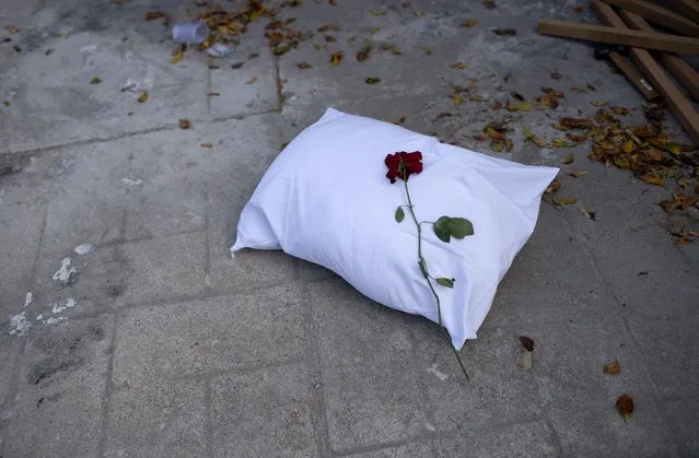 A pillow with a rose sits on the sidewalk during a protest against the Government's handling of the COVID-19 pandemic, organized by the Rio de Paz NGO in front of the Ronaldo Gazolla hospital in Rio de Janeiro, Brazil, Wednesday, March 24, 2021. (Photo by Silvia Izquierdo/AP Photo)