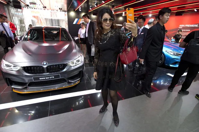 A woman poses for a selfie near the latest car models from BMW displayed at Auto China 2016 in Beijing, China, Monday, April 25, 2016. (Photo by Ng Han Guan/AP Photo)