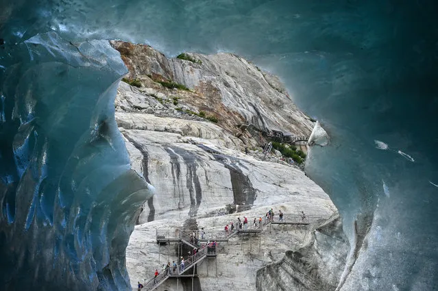 People walk on footbridges as they visit “La Grotte de Glace” (Ice cave) on July 19, 2019 on the largest French glacier, “Mer de Glace” (Sea of Ice), in Chamonix-Mont-Blanc, in the French Alps, eastern France. At 7km long and 200 metres deep, the “Mer de Glace” (Sea of Ice) glacier, which is located on the northern slopes of the Mont Blanc massif, is France's largest glacier. (Photo by Philippe Desmazes/AFP Photo)