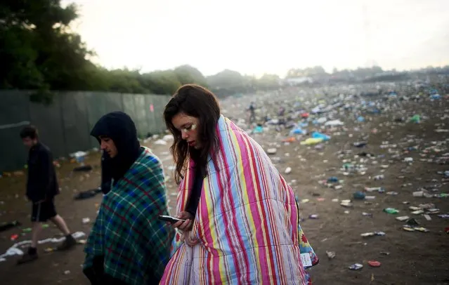 Revellers walk through rubbish left in front of the Pyramid Stage as they leave Worthy Farm in Somerset after the Glastonbury Festival in Britain June 29, 2015. (Photo by Dylan Martinez/Reuters)