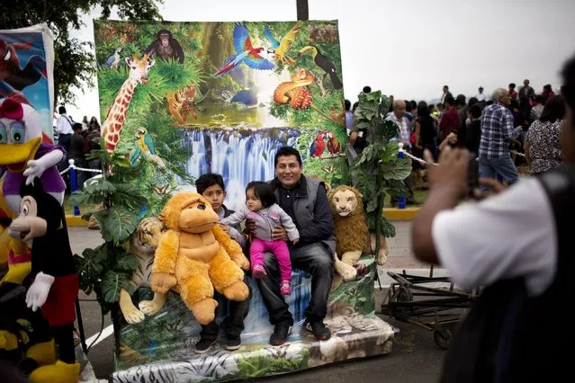 A family poses for a street photographer after a parade celebrating Saint Peter's day in Lima, Peru, Monday, June 29, 2015. (Photo by Rodrigo Abd/AP Photo)