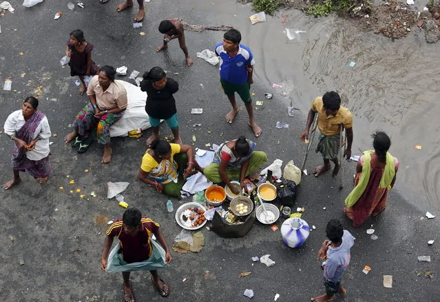 Displaced residents cook their meal on a flooded roadside in Chennai, India, December 3, 2015. (Photo by Anindito Mukherjee/Reuters)
