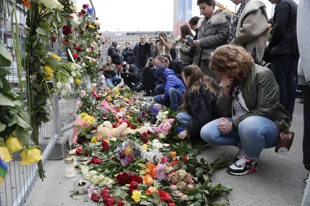 People lay down flowers at a fence near the department store Ahlens following a suspected terror attack in central Stockholm, Sweden, Saturday, April 8, 2017. (Photo by Markus Schreiber/AP Photo)
