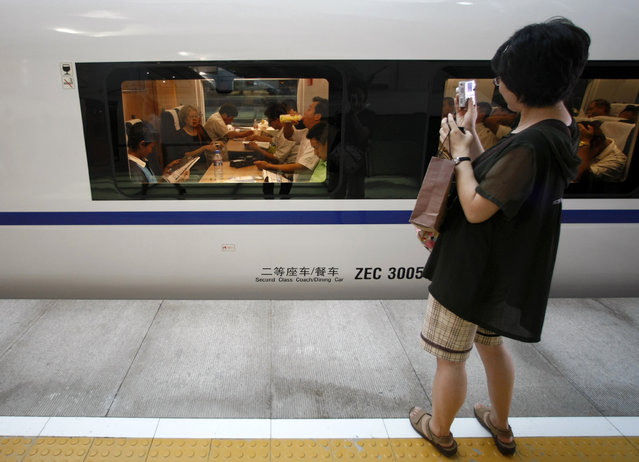 A woman takes pictures of the new Beijing-Tianjin Intercity Railway train at the station in Beijing, August 1, 2008. (Photo by Kim Kyung-Hoon/Reuters)