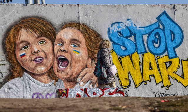 A woman passes a mural by Berlin-based street artist Eme Freethinker featuring Russian and Ukrainian girls in Berlin, Germany, Monday, February 28, 2022. (Photo by Hannibal Hanschke/AP Photo)