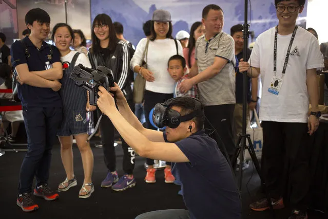 Spectators react as a visitor wearing a virtual reality headset plays an interactive video game at the G Festival, part of the Global Mobile Internet Conference (GMIC) in Beijing, Saturday, April 29, 2017. The GMIC features current and future trends in the mobile Internet industry by some major foreign and Chinese internet companies. (Photo by Mark Schiefelbein/AP Photo)
