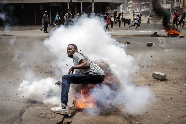 A protester reacts as a tear gas canister explodes on him during an anti-government demonstration called following nationwide deadly protests over tax hikes and a controversial now-withdrawn tax bill in downtown Nairobi, on July 2, 2024. (Photo by Luis Tato/AFP Photo)